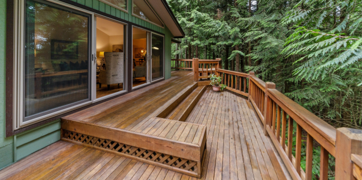 A wooden deck with benches and steps leading to the patio.