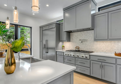 A kitchen with grey cabinets and white counters.